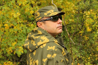 На фото человек в камуфляжном кепи с коротким козырьком. Снимок сделан в осеннем лесу.